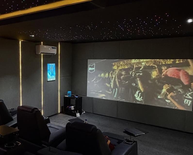 Home theater room with star ceiling, yellow wall lighting, and large projection screen.