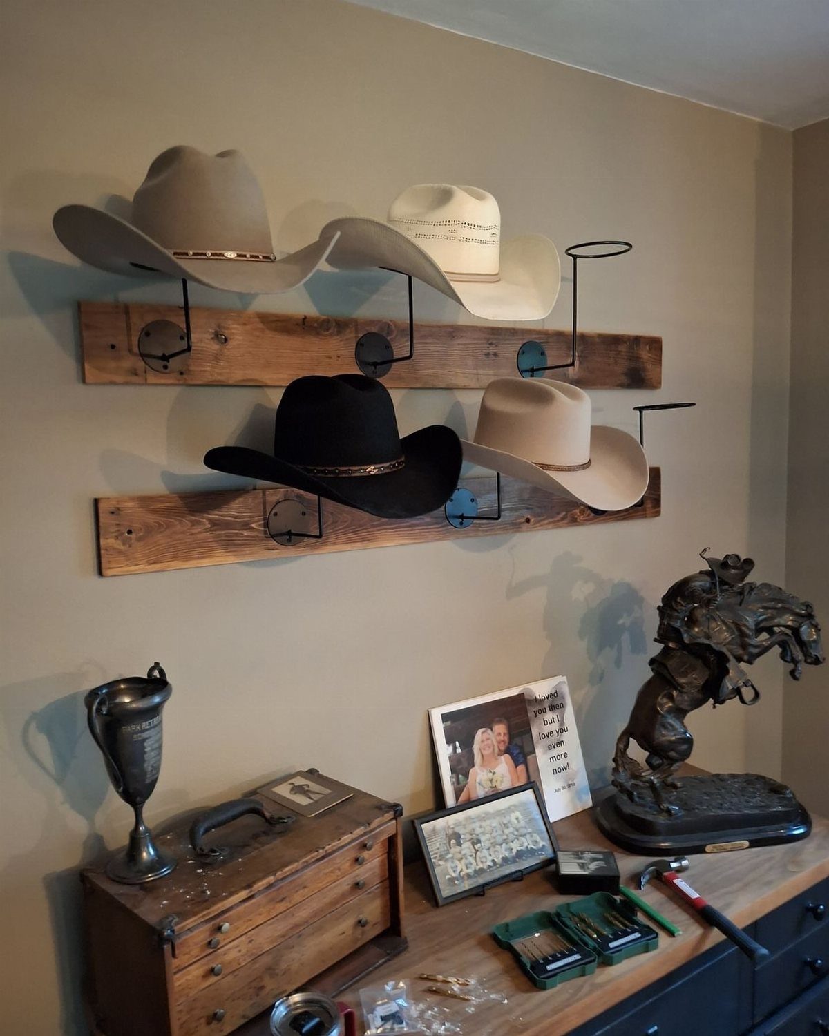 Cowboy hats hanging on metal hooks attached to rustic wooden wall planks.