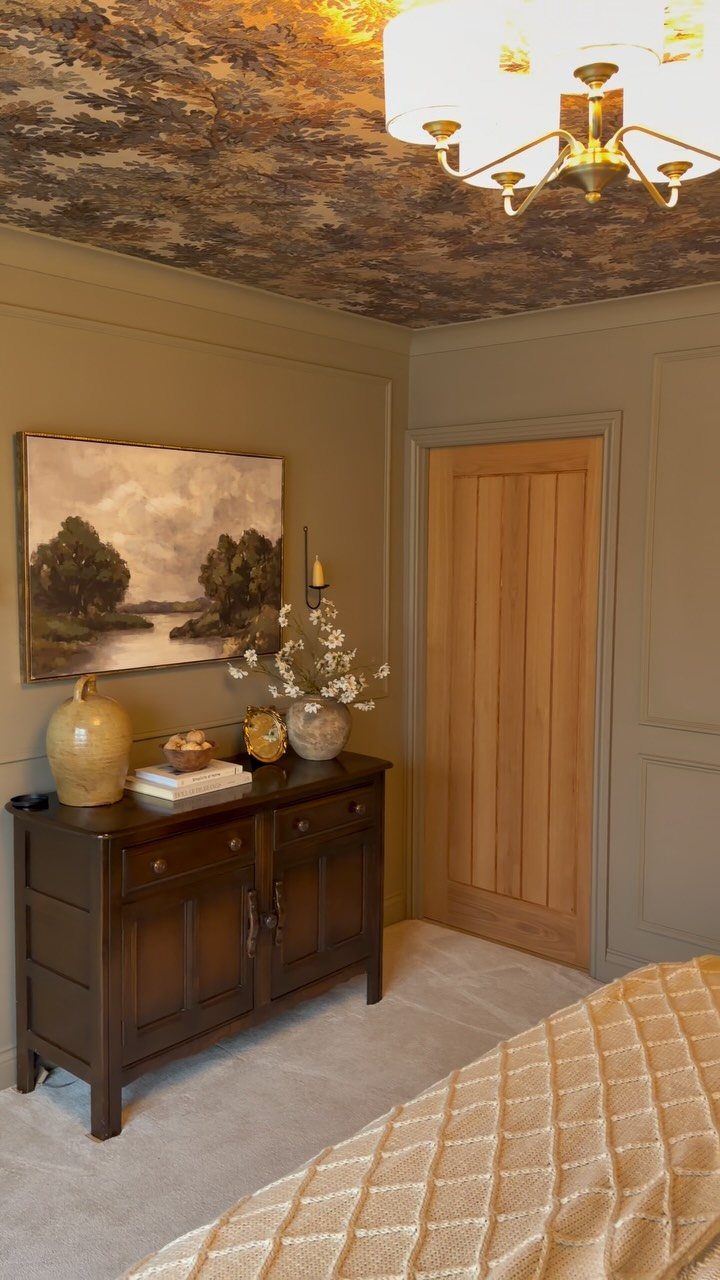 Bedroom ceiling covered in dark patterned wallpaper with a gold chandelier hanging below.