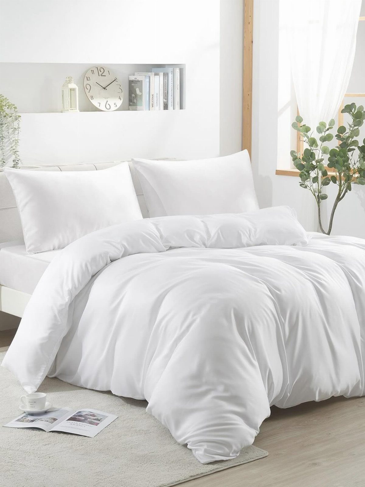 Bed with all white sheets and bedding in a bright, minimalist bedroom.