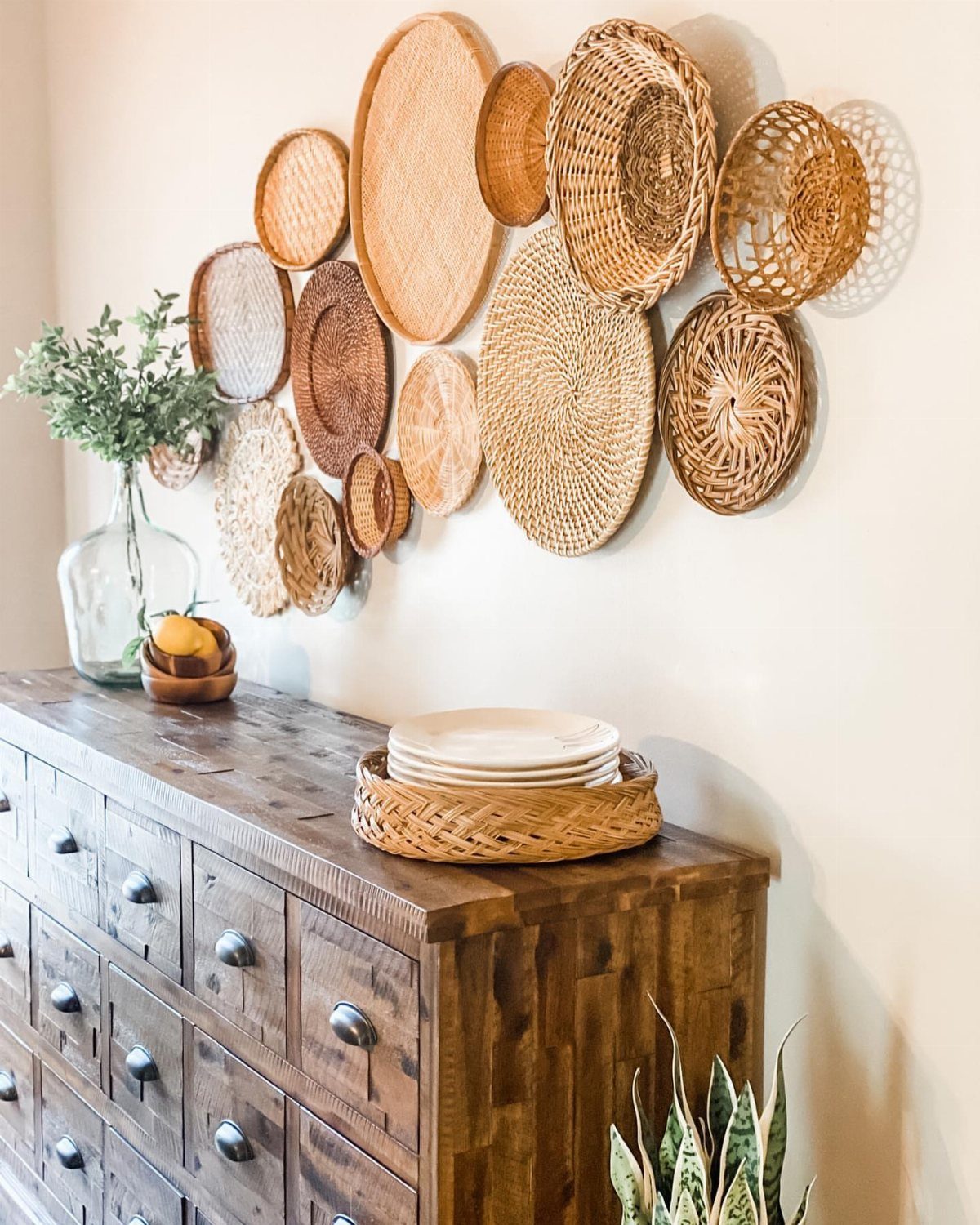 Woven wicker baskets and plates arranged as wall decor above a wooden dresser.
