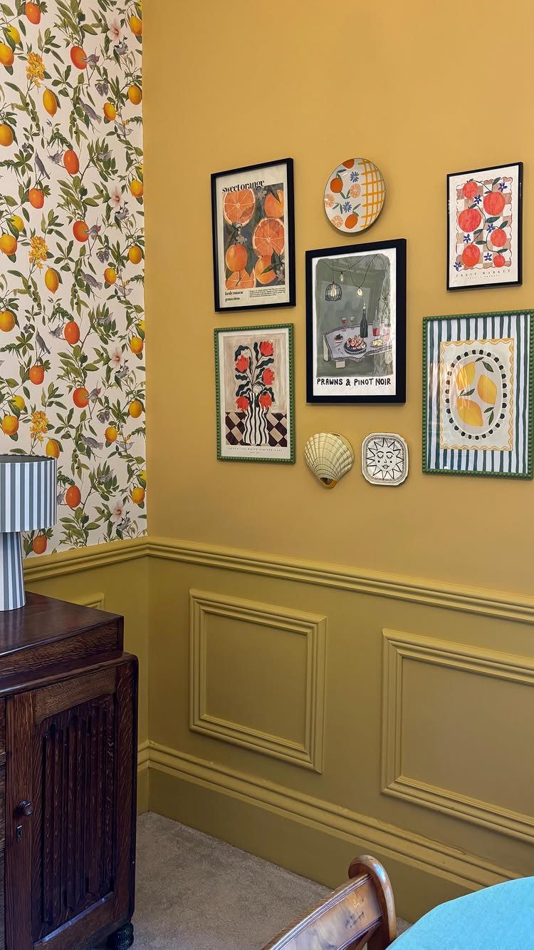 Gallery wall with framed art and plates on a yellow wall with wainscoting.