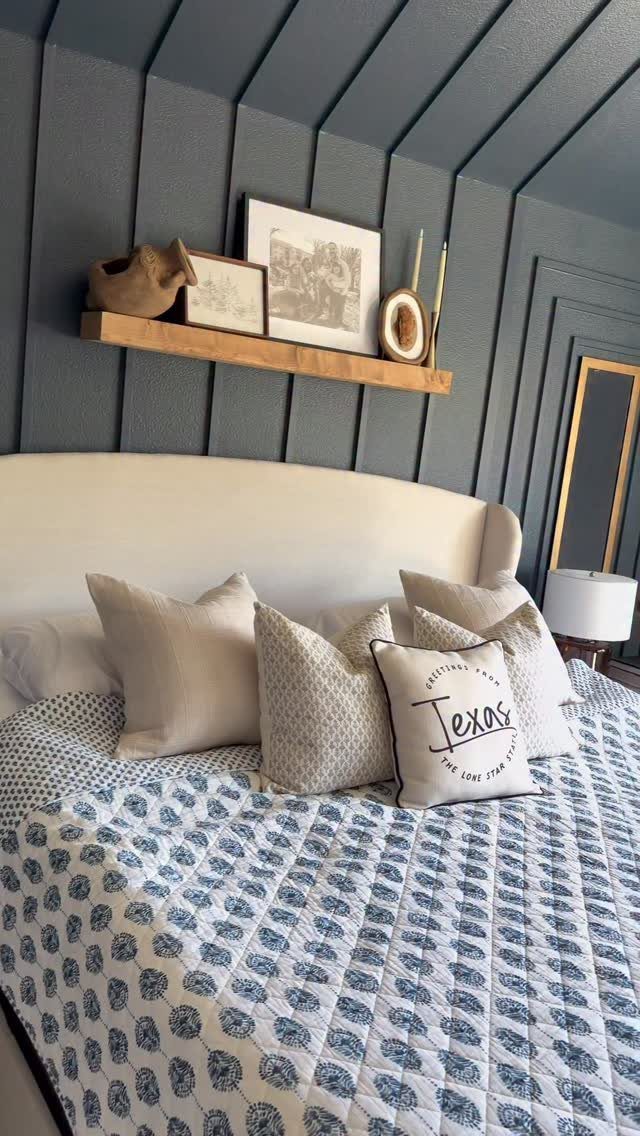 Bedroom with dark blue walls, vertical wooden trim, and a floating wooden shelf.