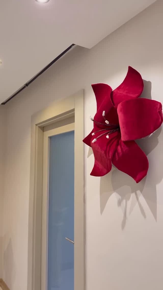 Large red 3D flower sculpture decorating a white wall next to a doorway.