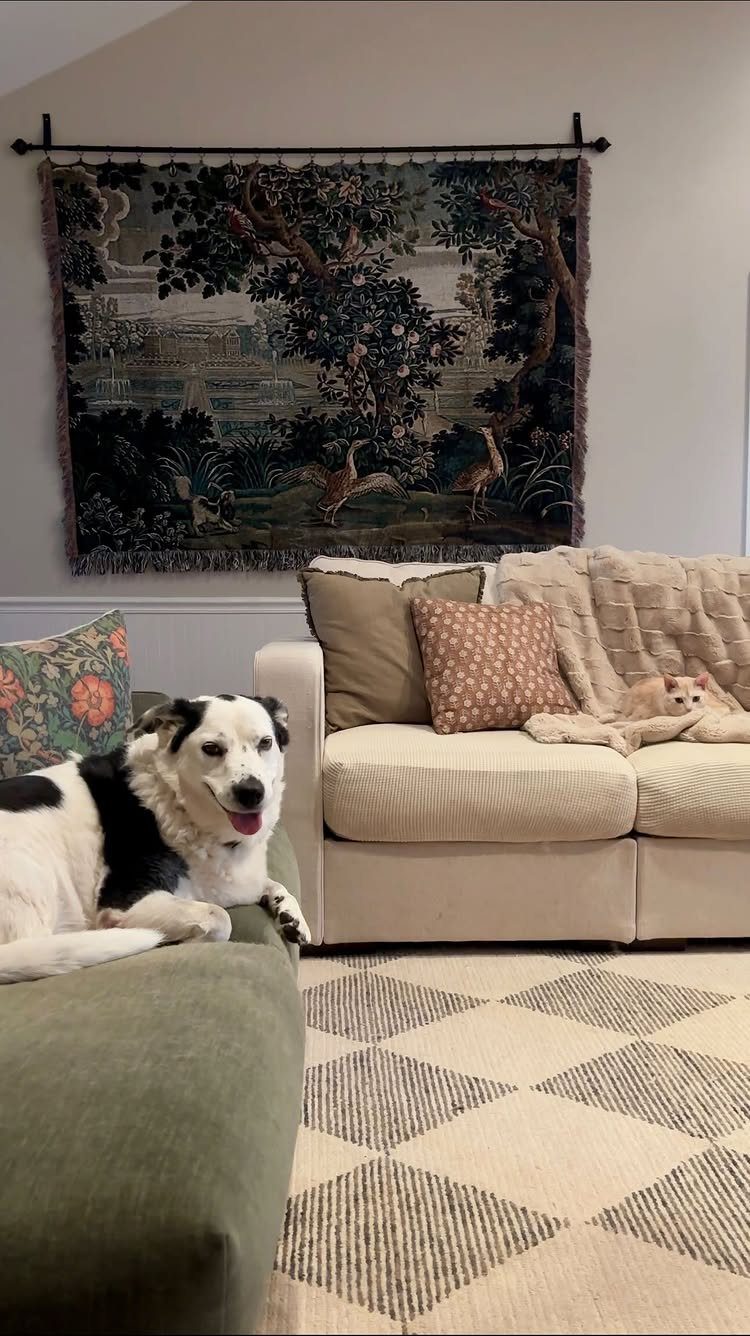 Large woven tapestry hanging on a wall above a beige sofa with pets.