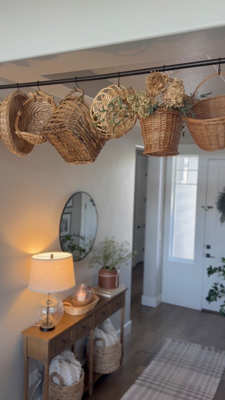 Woven wicker baskets hanging from a black rod along a white hallway wall