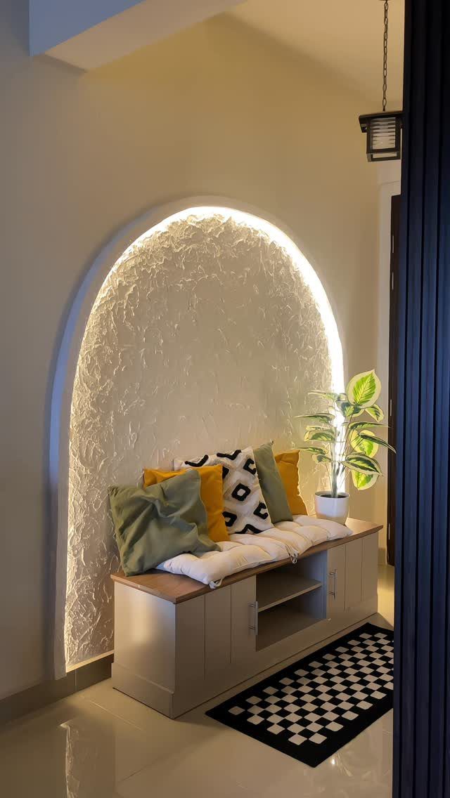 Arched wall niche with textured plaster, integrated lighting, and a cozy seating bench.