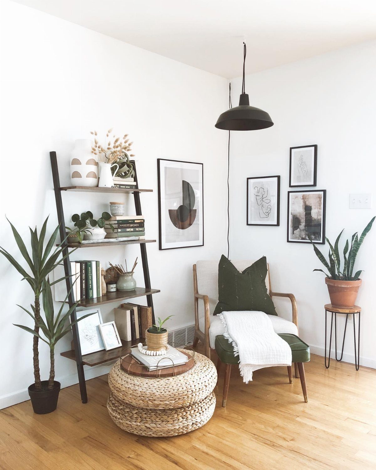 Corner gallery wall with framed art, a green armchair, and a leaning shelf.