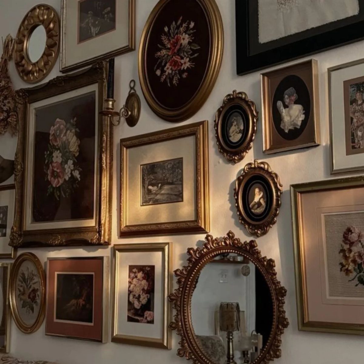 Ornate gold and black frames with floral art and mirrors on a white wall