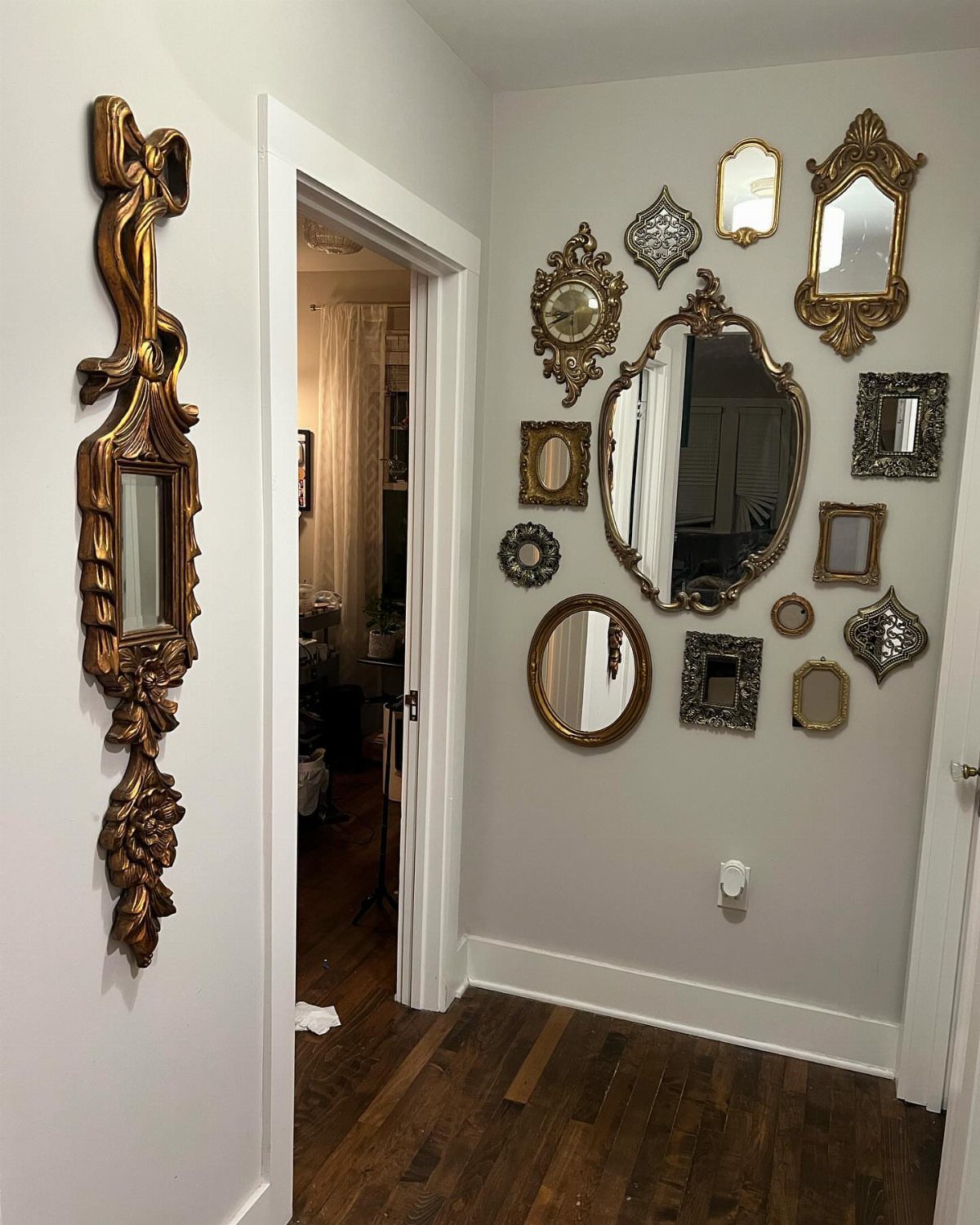 Ornate gold and silver mirrors of various shapes arranged on a grey wall.