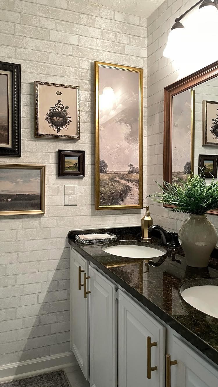 Framed art on a white brick wall above a bathroom vanity and mirror.