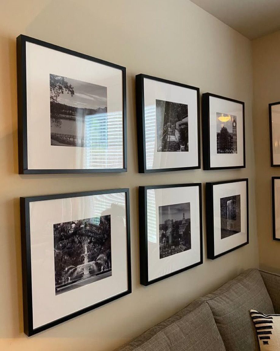 Black framed black and white photos arranged in two rows on a beige wall.