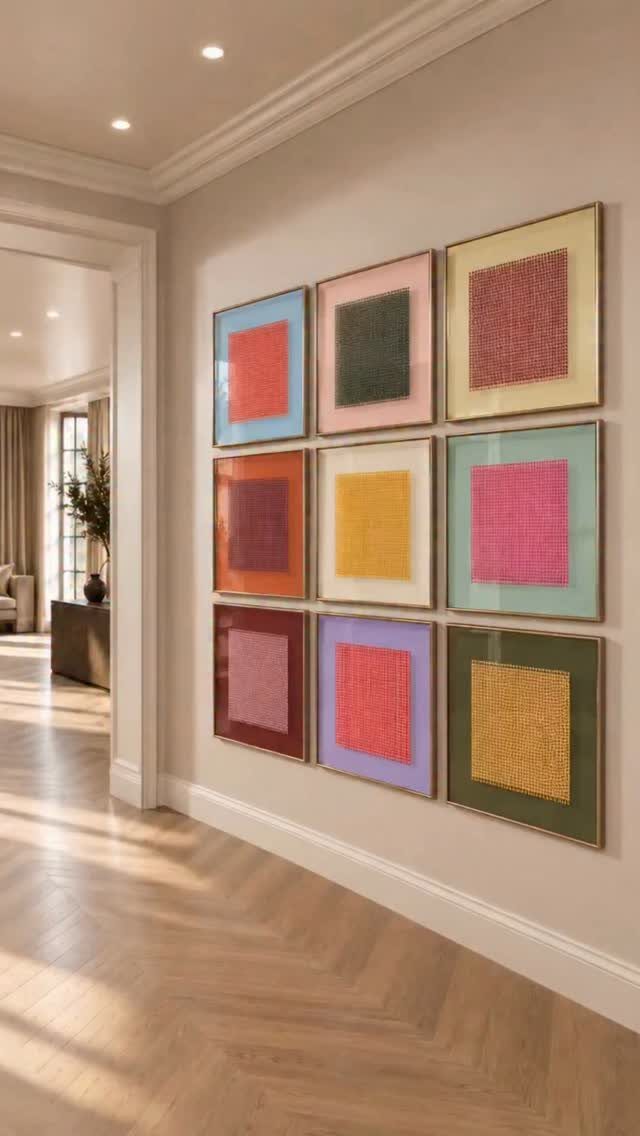 Nine colorful square framed artworks arranged in a symmetrical grid on a hallway wall.