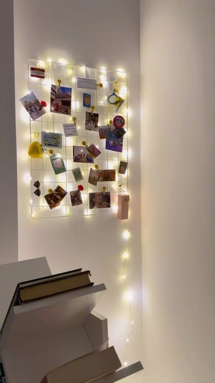 White wire grid wall organizer with photos, notes, and warm string lights.