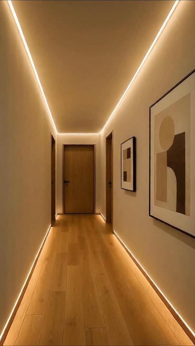 Narrow hallway with warm recessed LED strip lighting along the ceiling and floor.