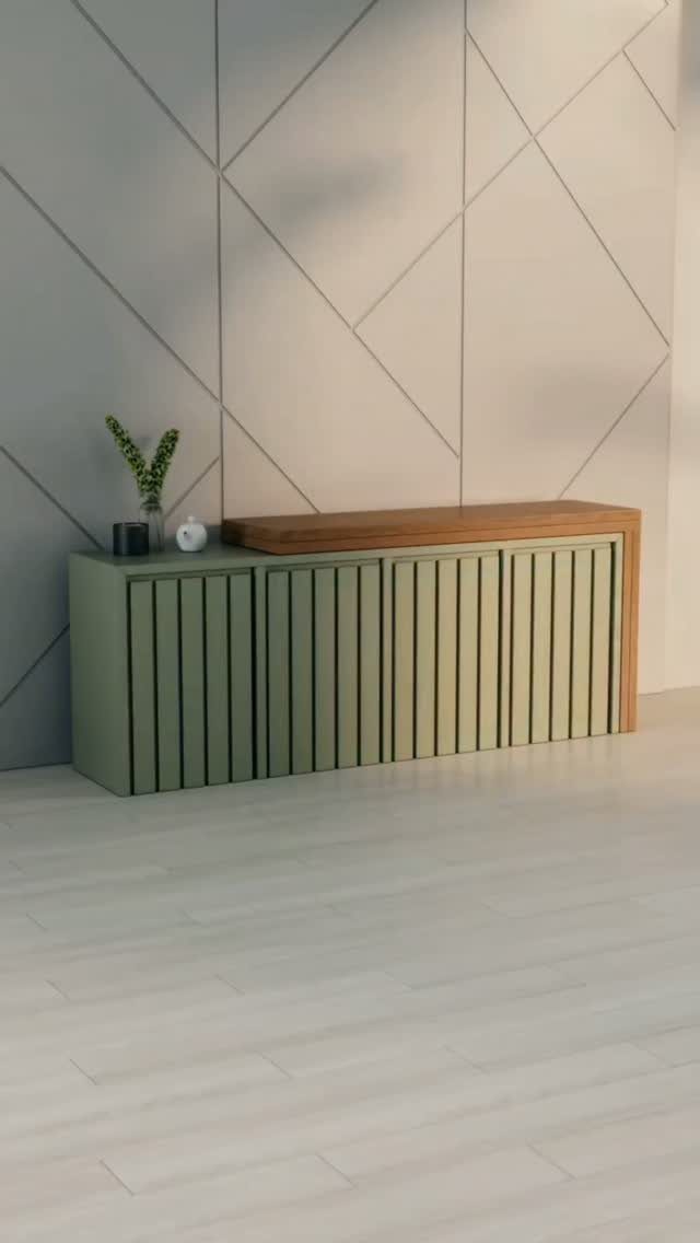 Sage green slatted cabinet with wooden top against a geometric grey wall.