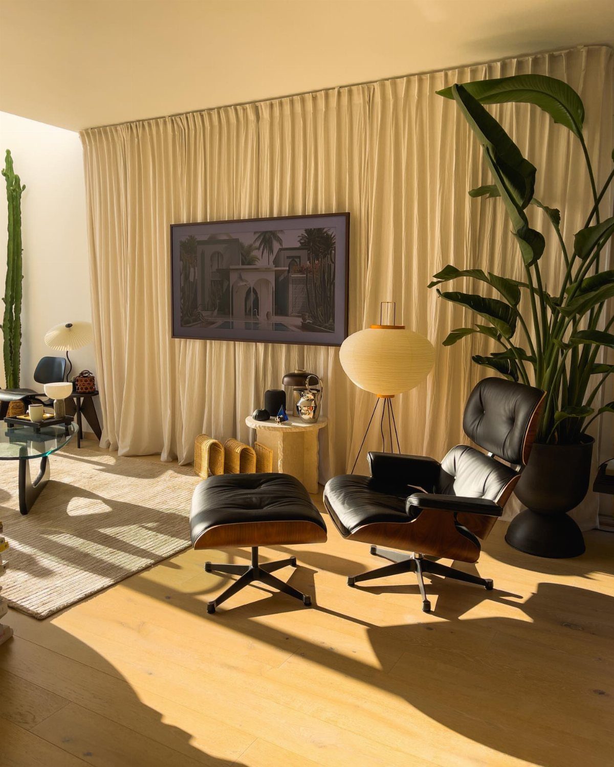 Mid-century modern living room with a framed painting, leather lounge chair, and large plant.