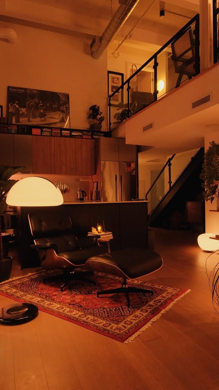 Black leather lounge chair and ottoman on a red rug in a modern loft.