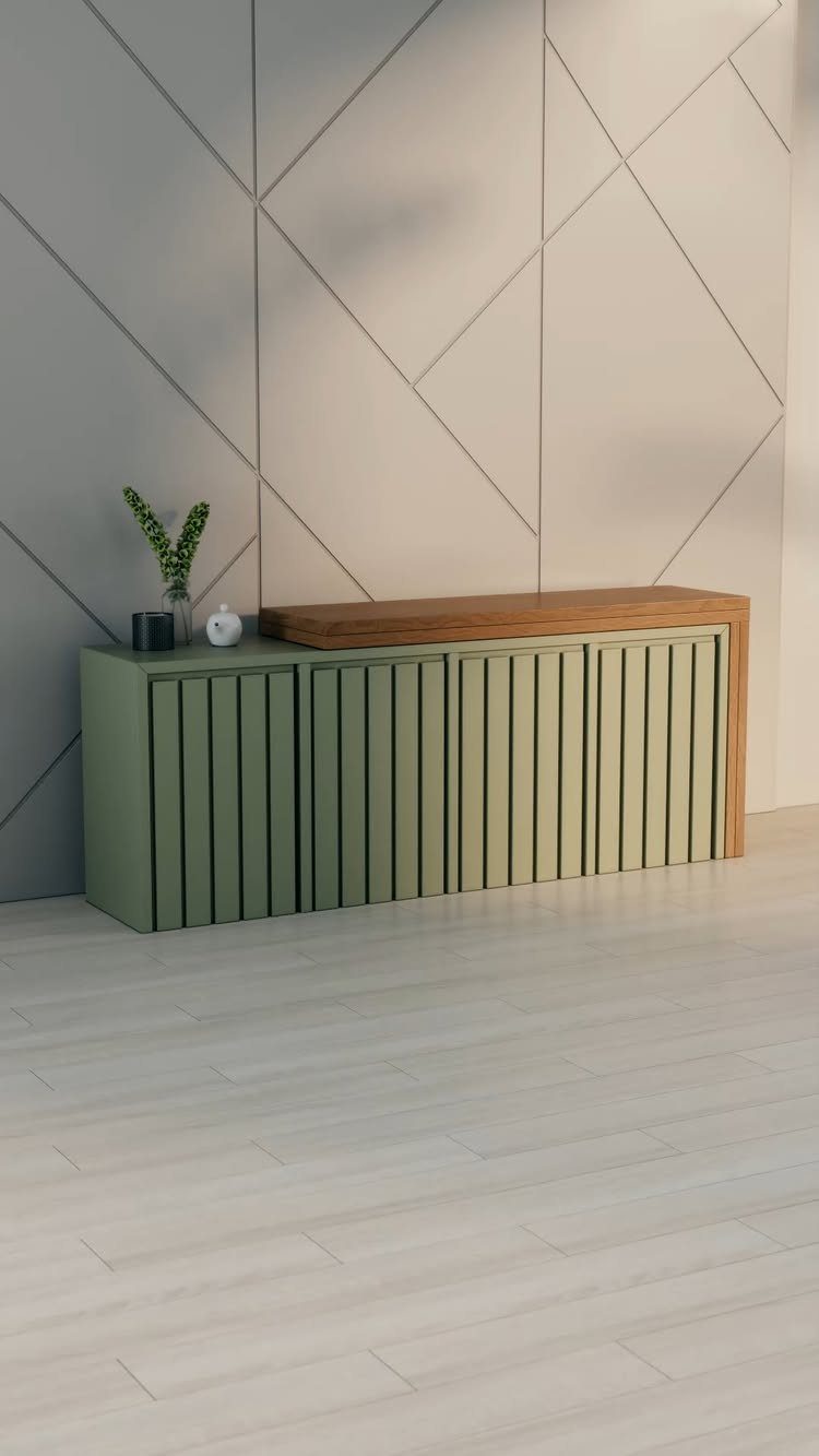 Olive green slatted sideboard with wood top against a geometric grey wall.