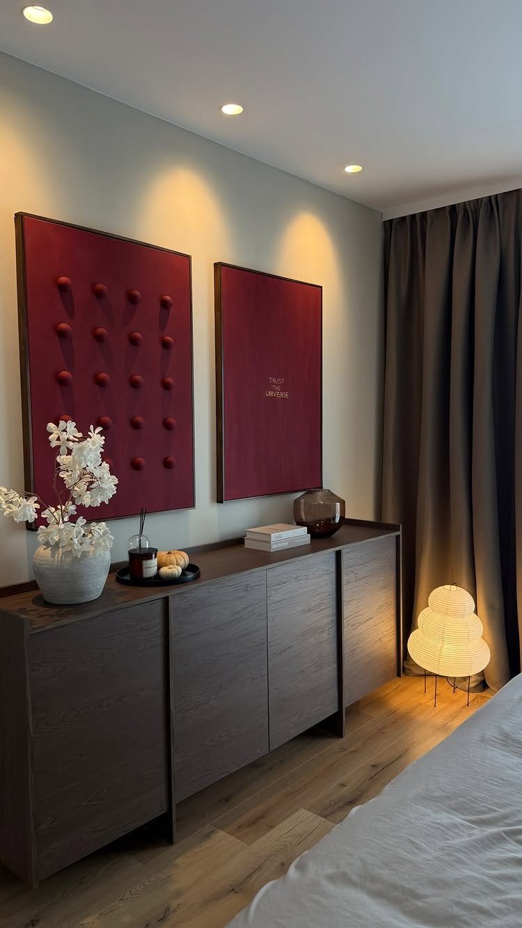 Two red rectangular art pieces hanging above a dark wood sideboard in a bedroom.