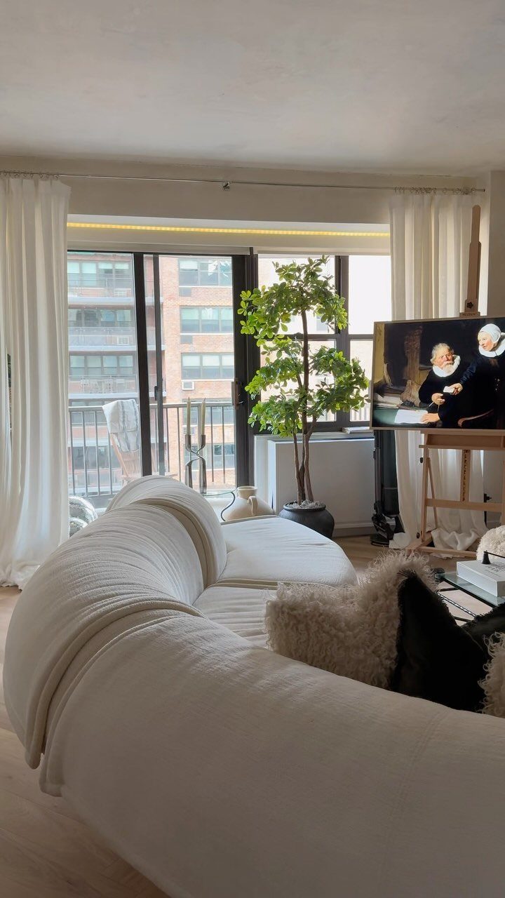 Modern living room with white curved sofa and city view through large windows