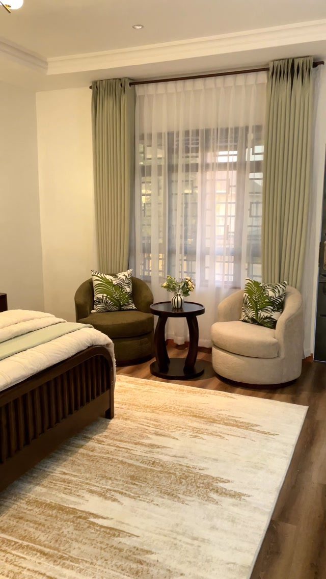 Olive green armchair and curtains in a bright, modern bedroom with neutral tones.
