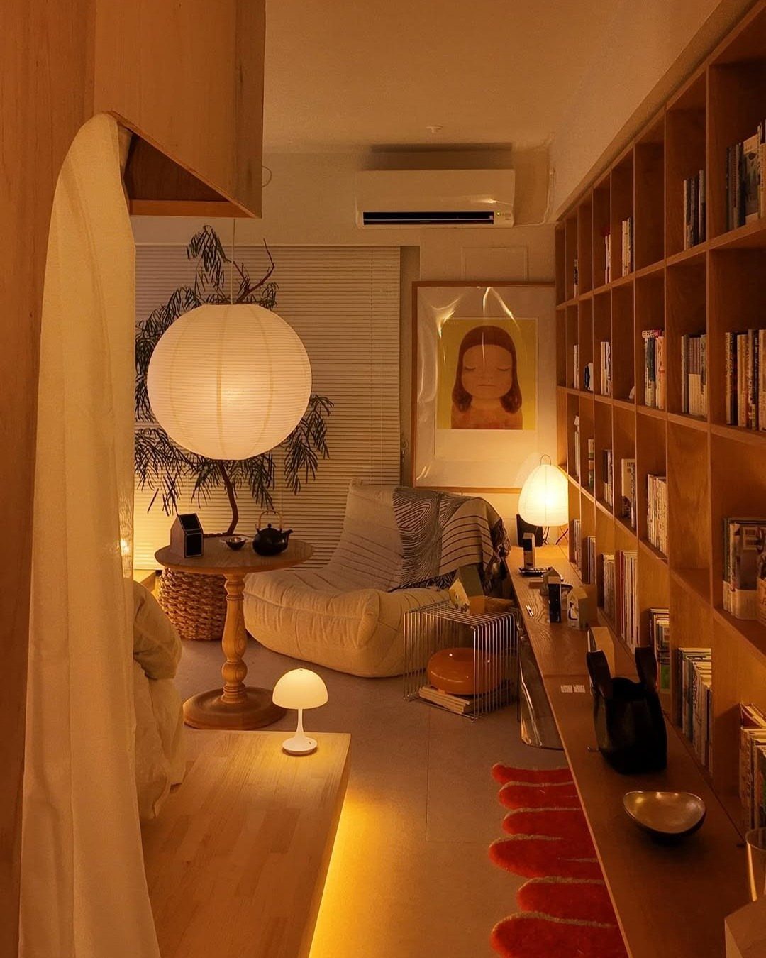 White paper globe pendant lamp and small table lamps illuminating a cozy wooden room