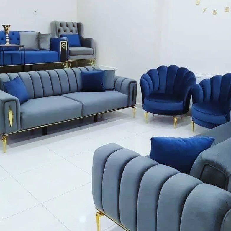 Light blue and royal blue velvet sofas and shell-shaped chairs in a white room.
