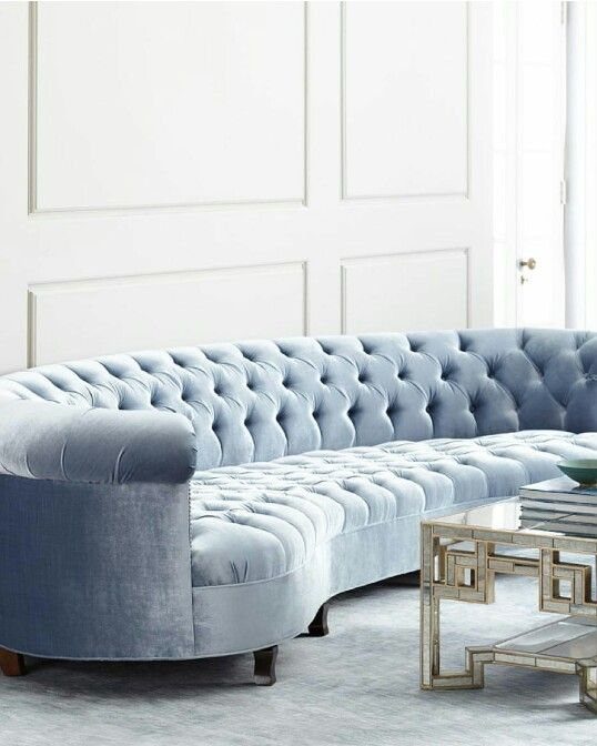 Light blue tufted velvet sofa in a bright room with white paneled walls.