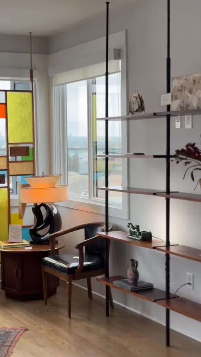 Floor-to-ceiling black metal shelving unit with wooden shelves in a modern living room.