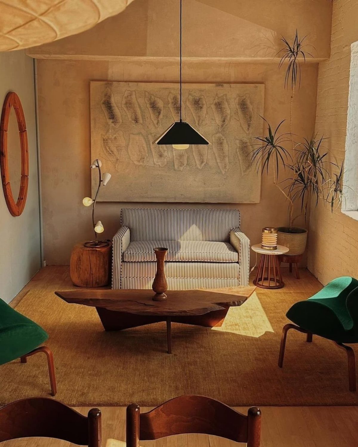 Mid century modern living room with green chairs, striped sofa, and wooden coffee table.