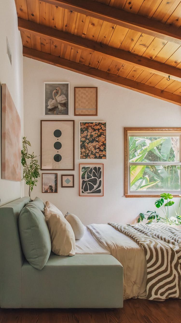 Gallery wall with modern art prints in wooden frames above a cozy bed.