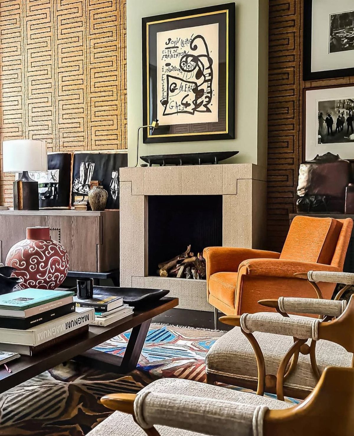 Orange and wooden armchairs in a living room with a stone fireplace.