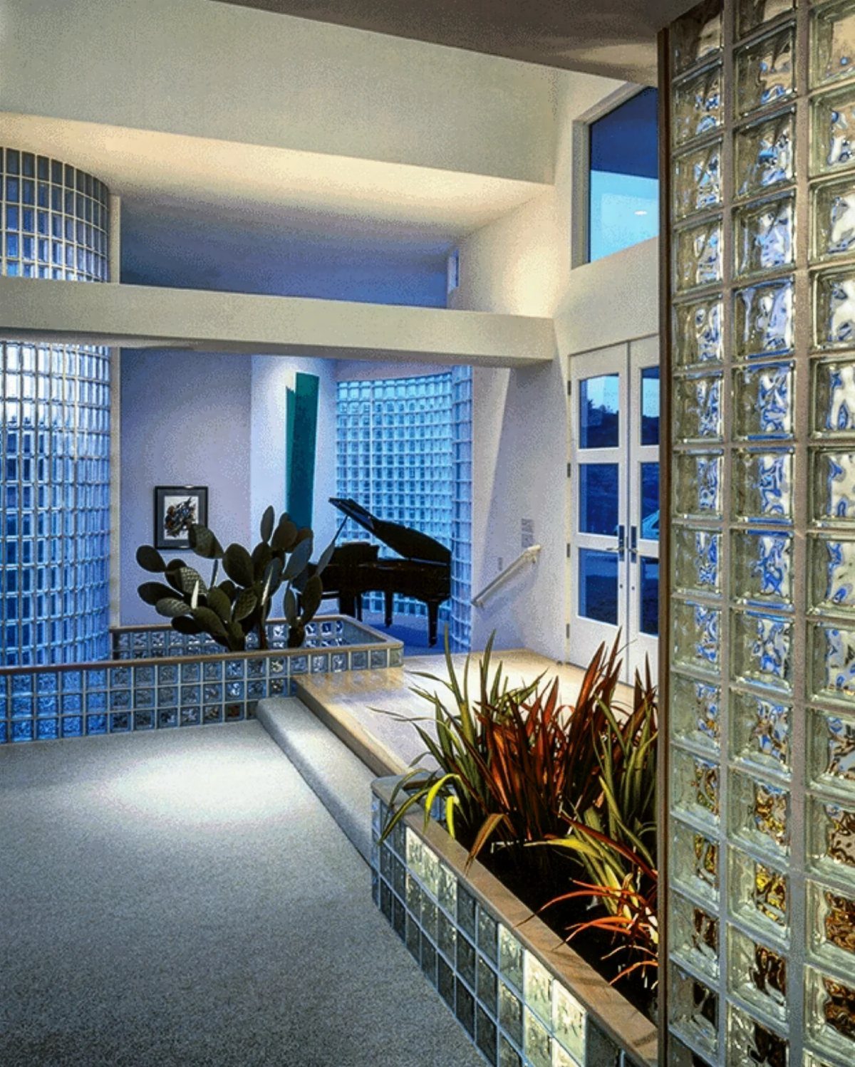 Glass block feature walls in a modern interior with a grand piano and plants.