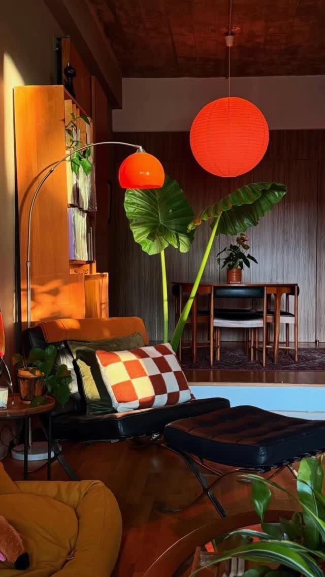 Mid-century modern living room with orange accent lighting and a black leather lounge chair.