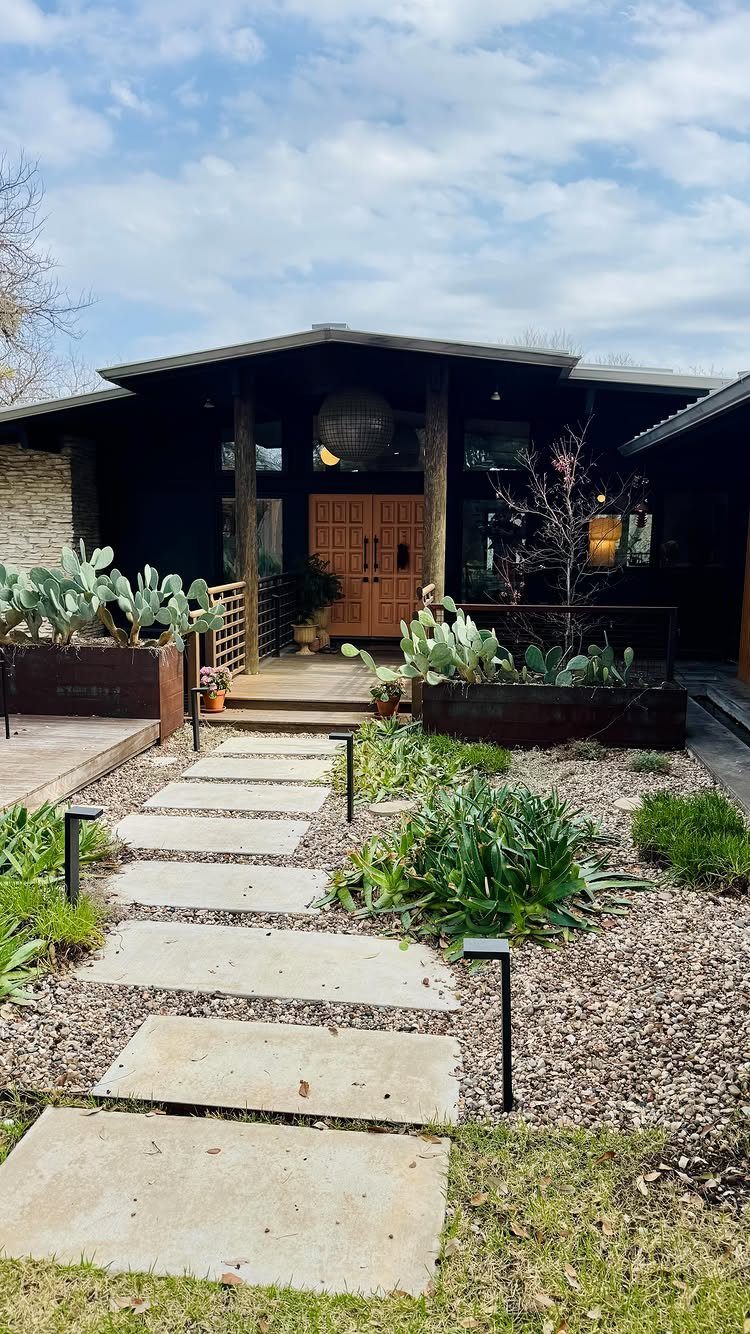 Mid-century modern house with rectangular concrete pavers leading to a wooden front door.