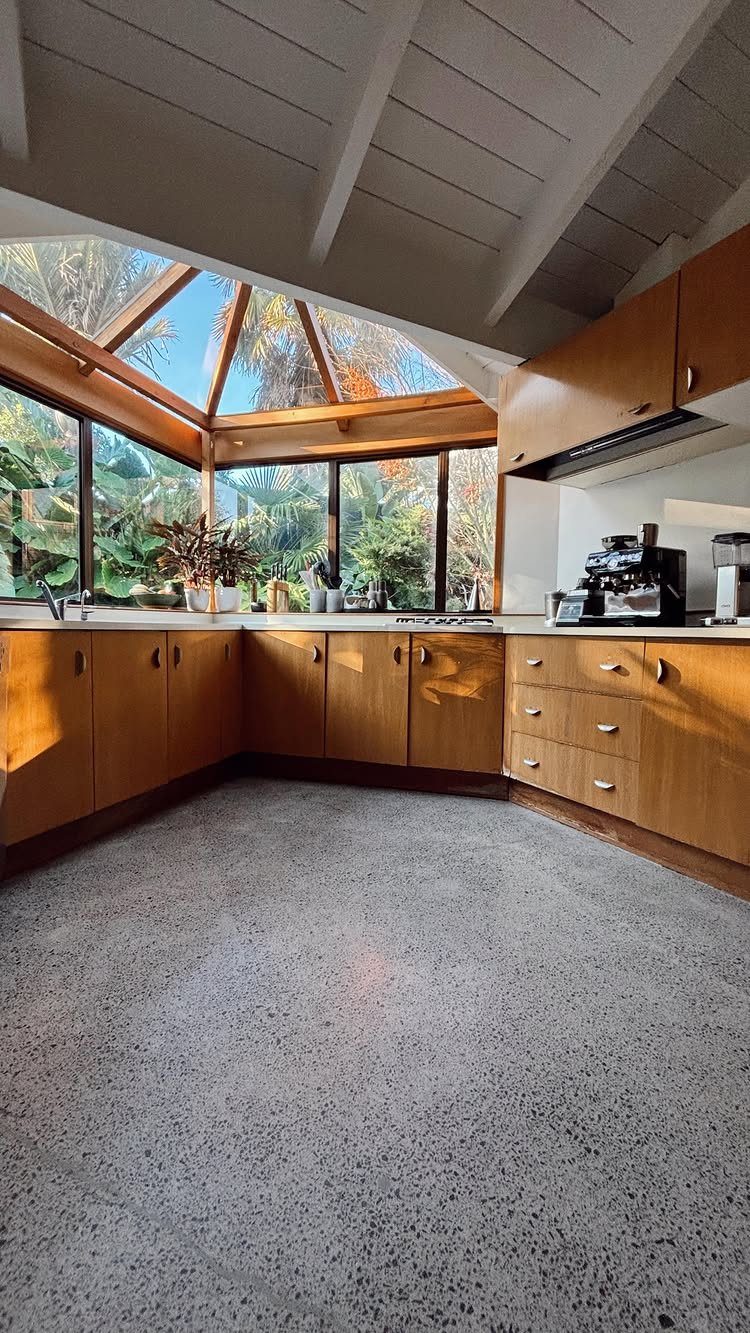 Mid-century modern kitchen with wood cabinets, terrazzo flooring, and large glass windows.