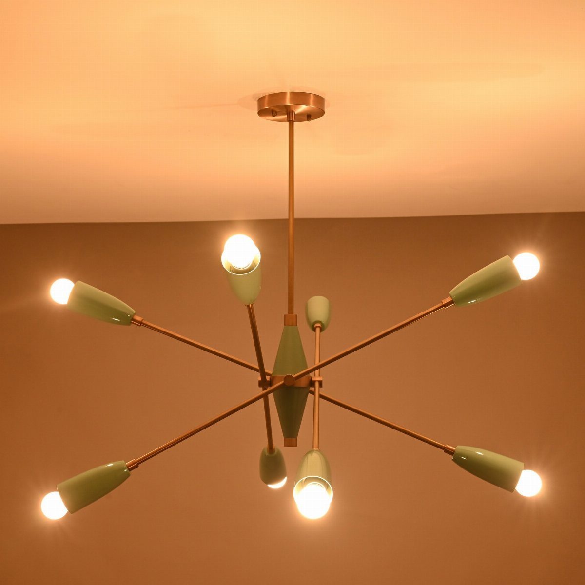 Sputnik chandelier with gold arms and pale green shades against a plain ceiling.