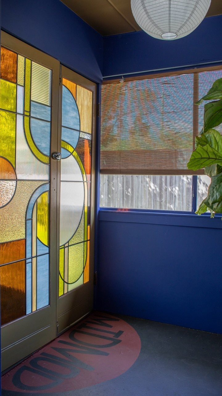 Stained glass double doors with geometric patterns in a deep blue room.