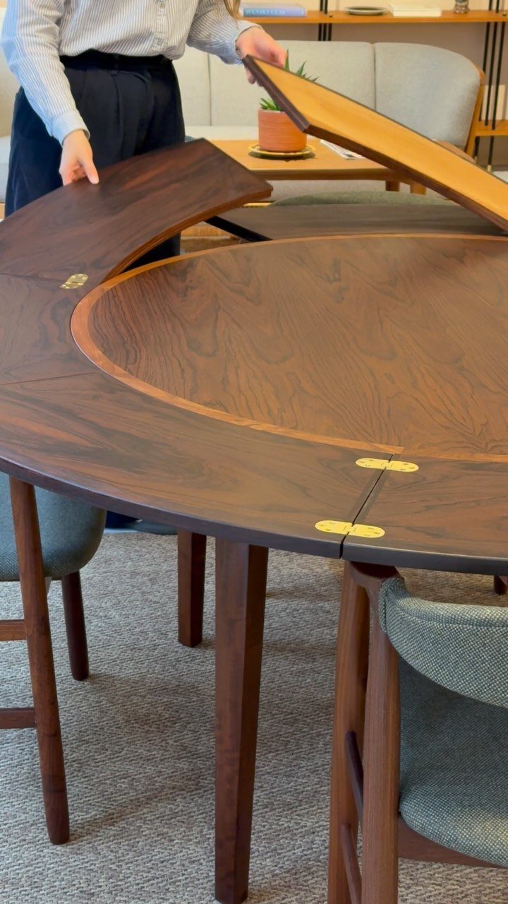 Round walnut dining table and chairs with tapered legs in a modern room