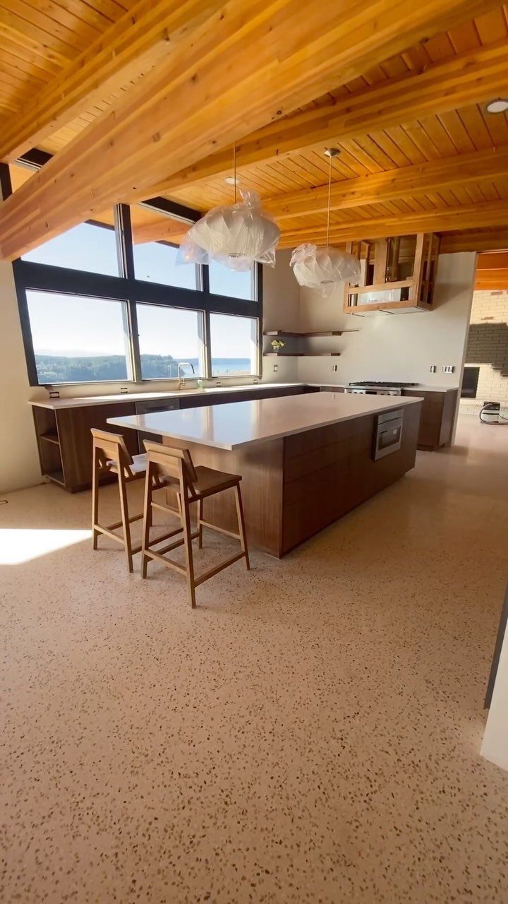 Speckled terrazzo flooring in a modern kitchen with wooden ceilings and island.