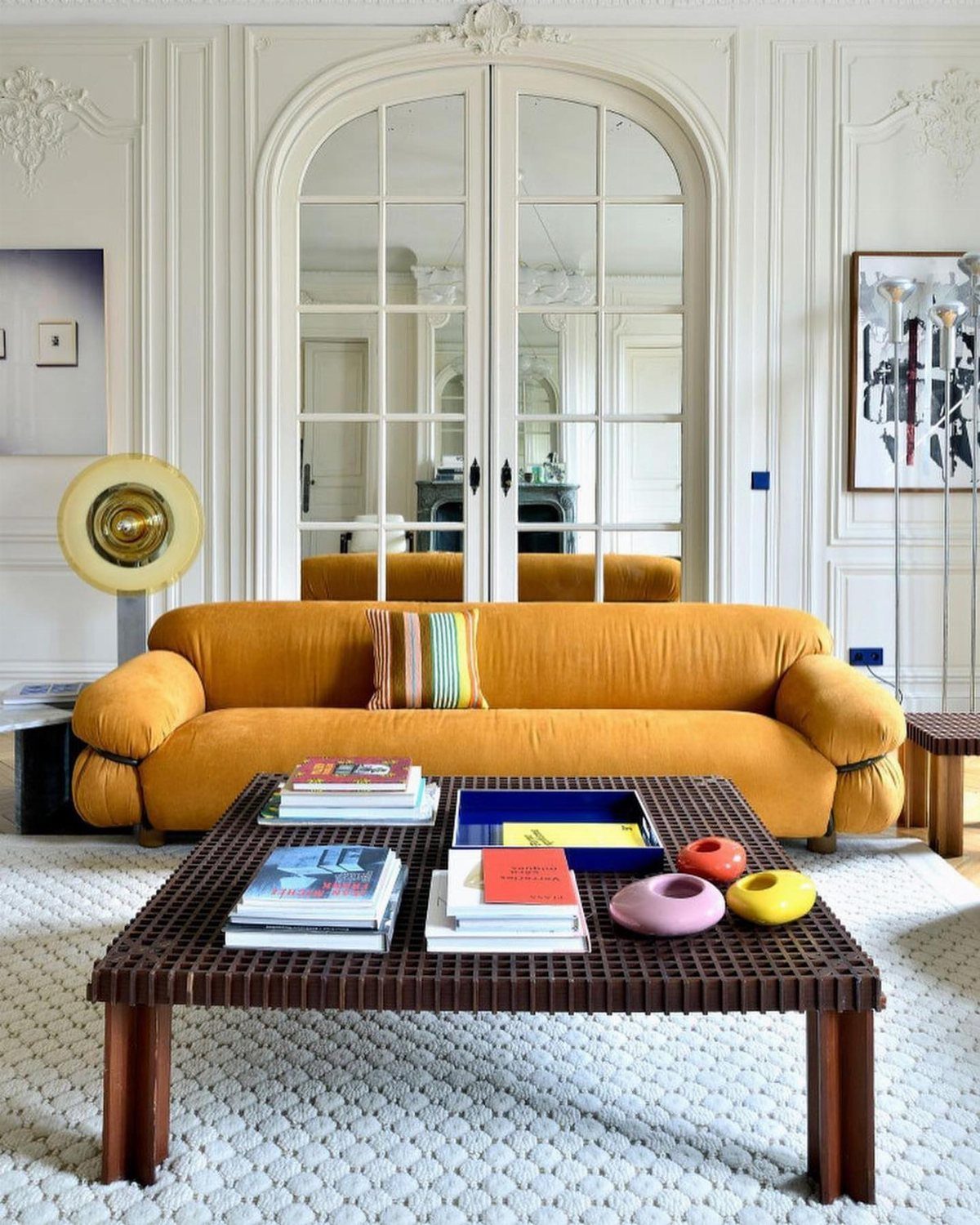 Mustard yellow curved sofa and woven coffee table in a bright white room