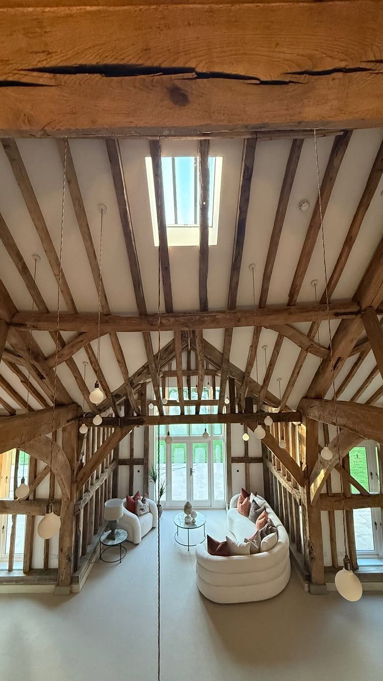 Exposed wooden beams and rafters in a bright, modern barn living room.