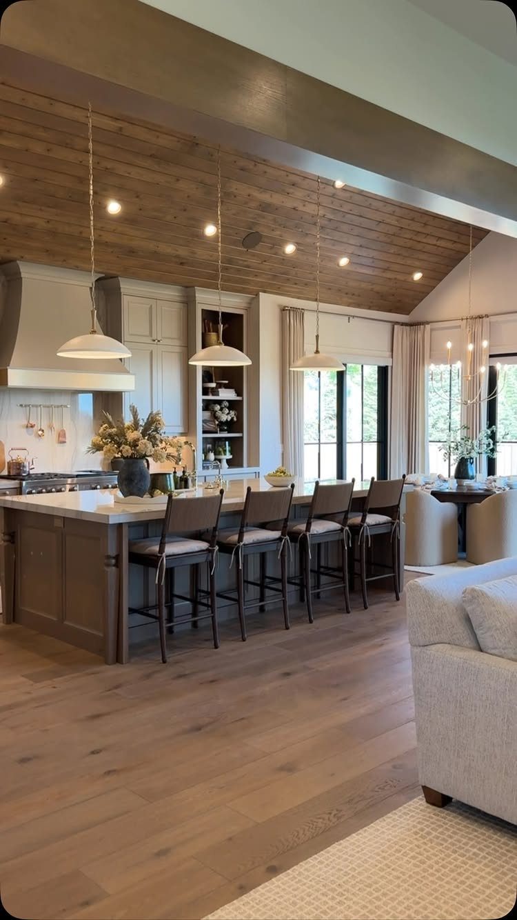 Modern kitchen with a sloped wooden plank ceiling and large central island.