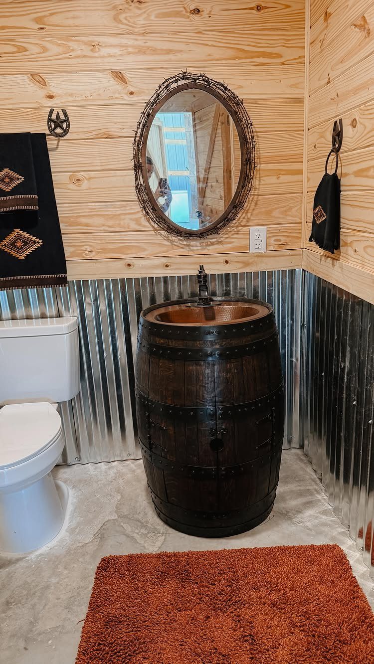 Wooden barrel sink in a rustic bathroom with corrugated metal walls and wood paneling.