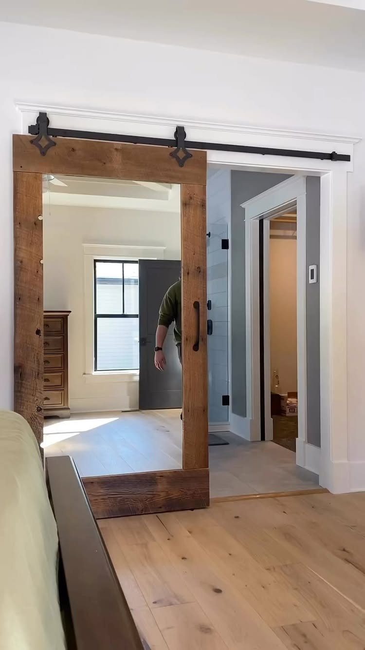 Wooden sliding barn door on a black track opening into a bright room.