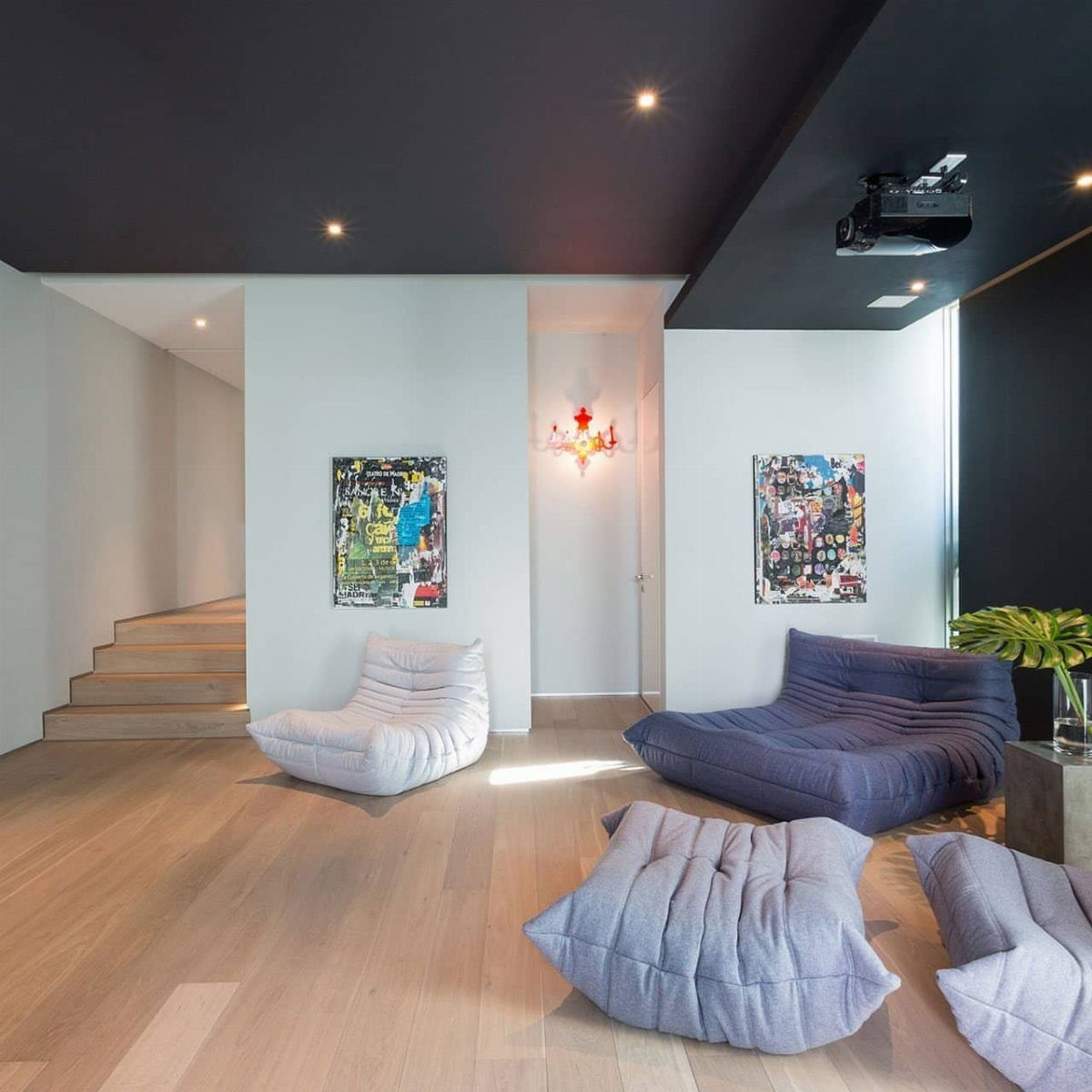 Matte black ceiling with recessed lighting in a modern living room with lounge chairs.