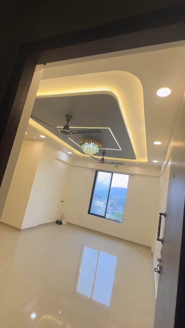 Multi-layered drop ceiling with grey and white panels and warm cove lighting.