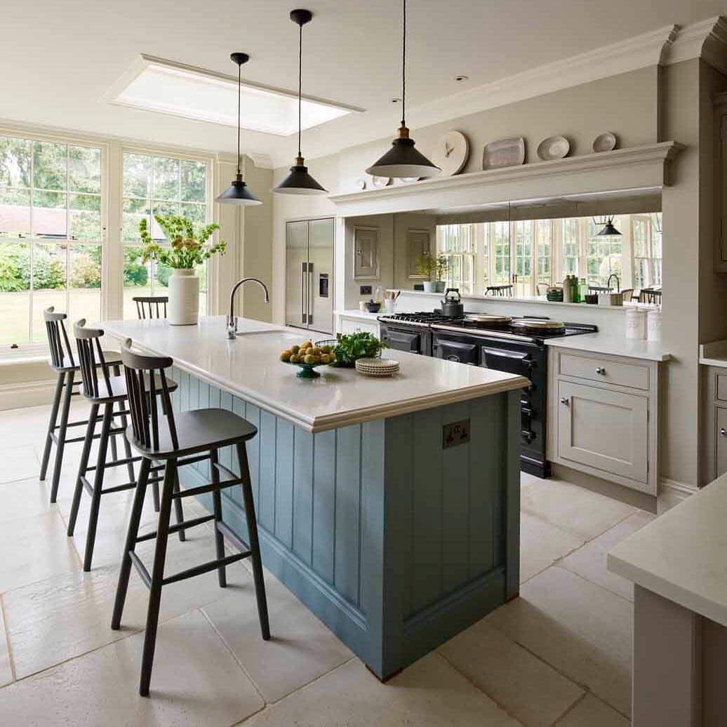 Blue kitchen island with white countertop and black stools in a bright room