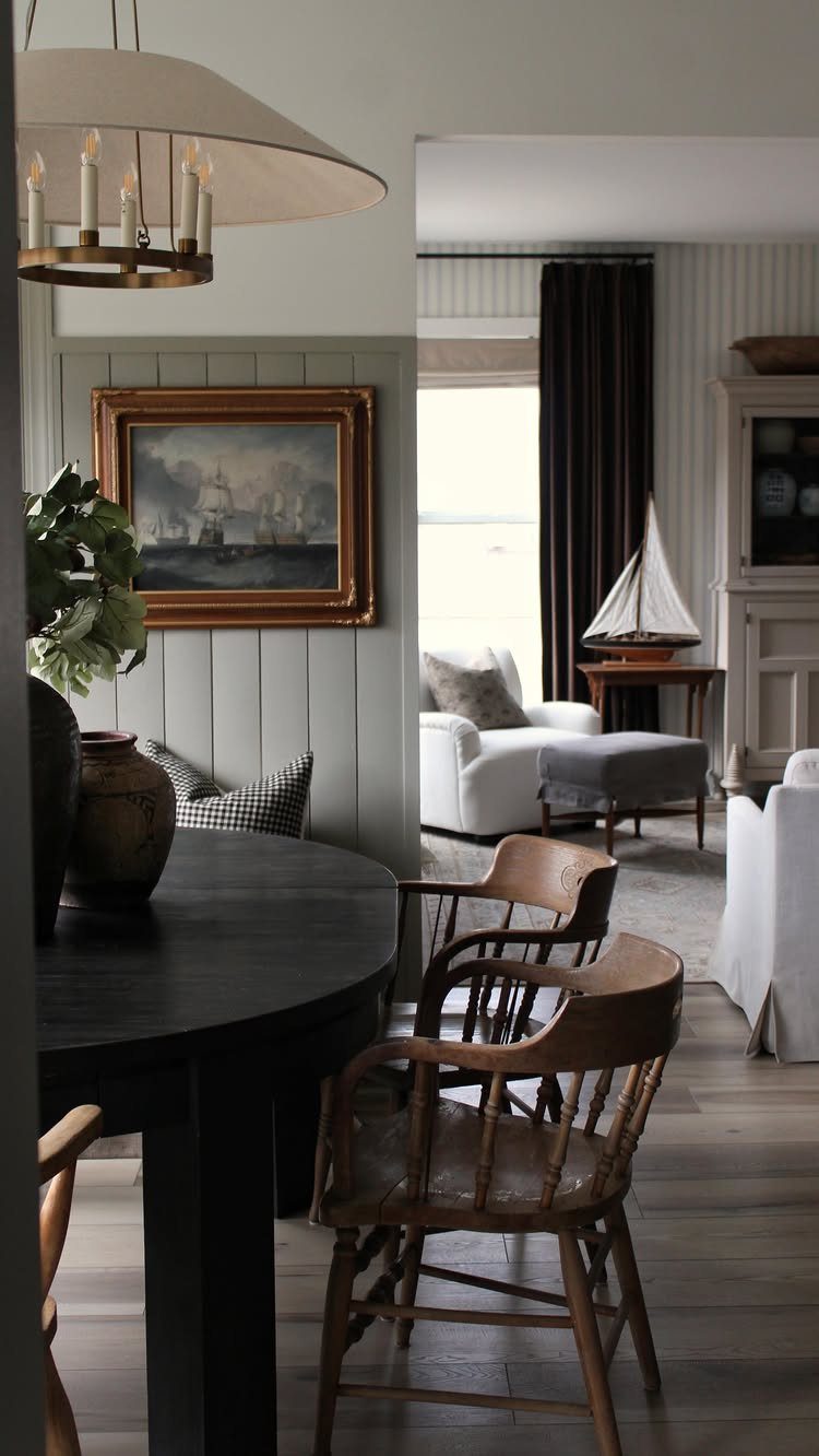 Dark dining table and wooden chairs in a modern English cottage interior.
